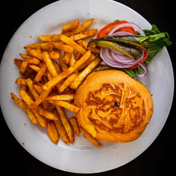 A Z Cafe & Bar burger with pickles, onions, tomato, lettuce, and a side of fries.