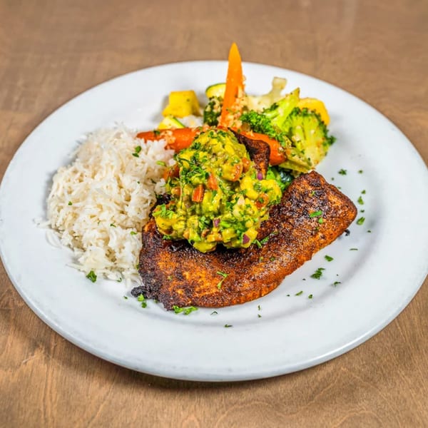 Blackened fish topped with avocado salsa, served with white rice and roasted vegetables.