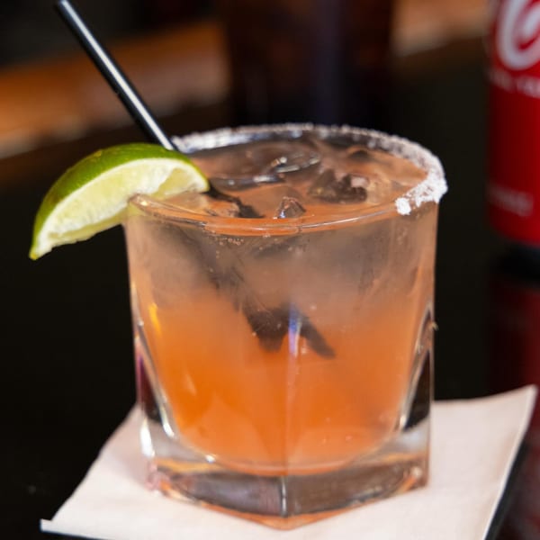 A Z Cafe & Bar cocktail, orange with ice, a lime wedge, and a salted rim.